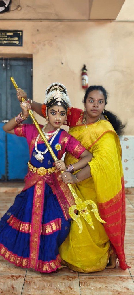 Seated classical dancer pose with golden trishula (trident)